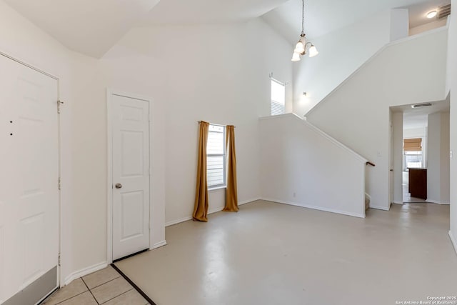 unfurnished living room with high vaulted ceiling, a wealth of natural light, and a notable chandelier