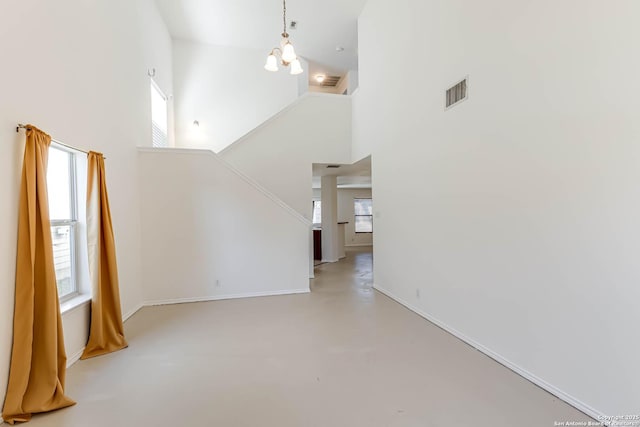 unfurnished living room featuring a towering ceiling and a chandelier