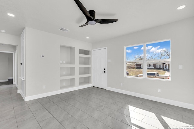 tiled empty room with ceiling fan and built in features