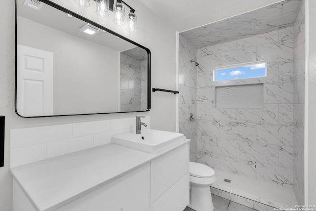 bathroom with tiled shower, vanity, toilet, and tile patterned flooring