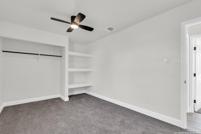 unfurnished bedroom with dark colored carpet, ceiling fan, and a closet