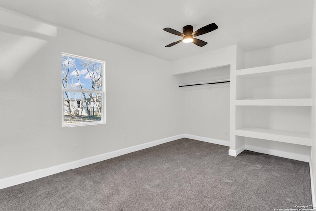 interior space featuring built in shelves, ceiling fan, and dark colored carpet