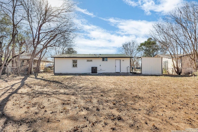 rear view of house featuring central air condition unit and a storage shed