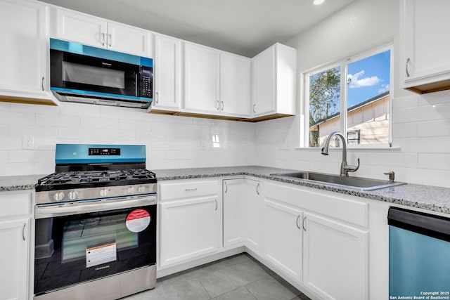 kitchen featuring light stone countertops, stainless steel appliances, sink, white cabinetry, and light tile patterned flooring