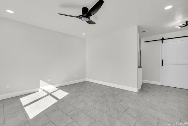 tiled spare room with a barn door and ceiling fan