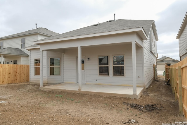 view of front of home with a patio, roof with shingles, and a fenced backyard