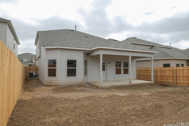 back of property with central air condition unit, a patio, roof with shingles, and a fenced backyard