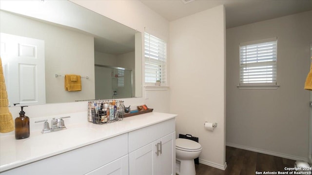 bathroom featuring wood-type flooring, vanity, toilet, and walk in shower