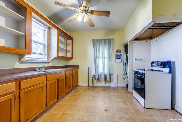 kitchen featuring ceiling fan, white range with gas stovetop, and sink