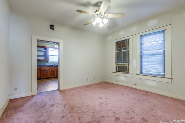 empty room featuring cooling unit, light carpet, and ceiling fan