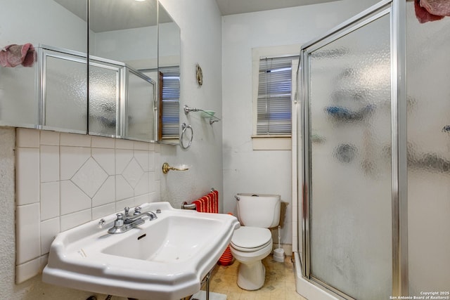 bathroom with decorative backsplash, toilet, a shower with shower door, and sink