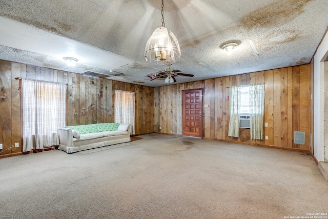 interior space featuring a textured ceiling, ceiling fan, cooling unit, and wood walls