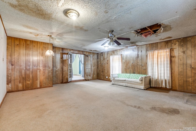 unfurnished room featuring carpet, a textured ceiling, ceiling fan, and wood walls