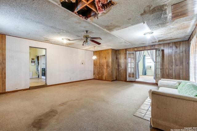 unfurnished living room with carpet, ceiling fan, and wood walls