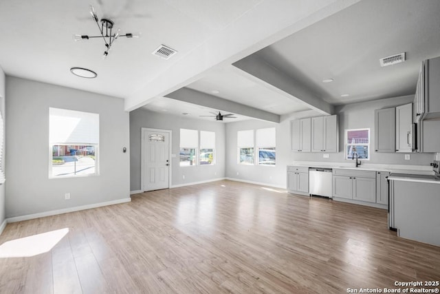 kitchen featuring beam ceiling, gray cabinetry, sink, stainless steel dishwasher, and light hardwood / wood-style floors