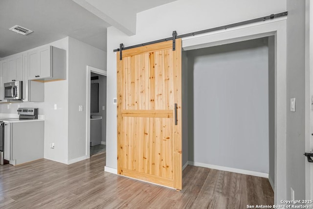 kitchen featuring electric range oven, a barn door, and light hardwood / wood-style flooring