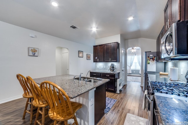 kitchen featuring a kitchen bar, appliances with stainless steel finishes, an island with sink, and sink