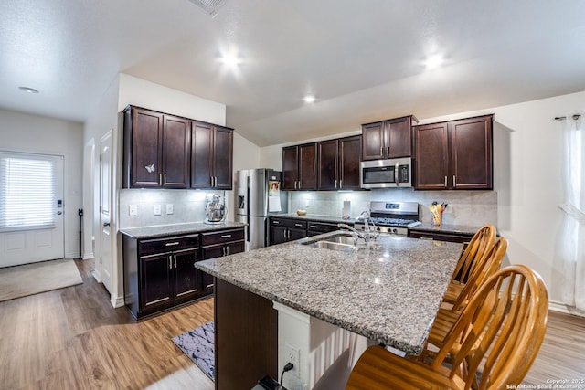 kitchen featuring appliances with stainless steel finishes, dark brown cabinetry, sink, a center island with sink, and a breakfast bar area