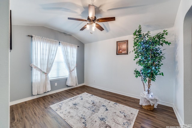 empty room featuring dark hardwood / wood-style flooring, vaulted ceiling, and ceiling fan