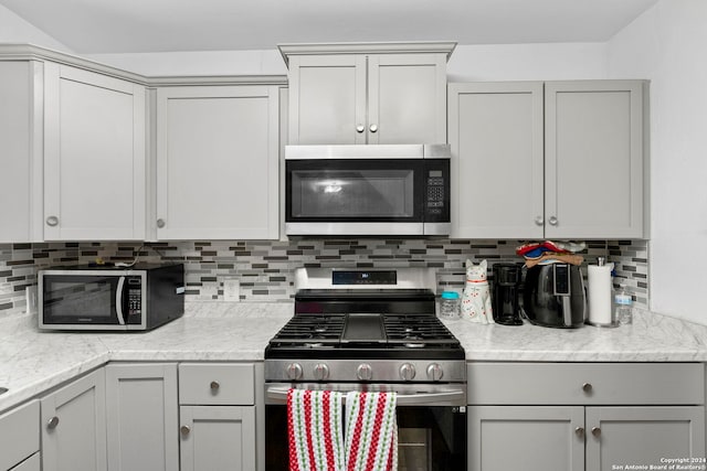 kitchen featuring decorative backsplash, appliances with stainless steel finishes, and light stone countertops