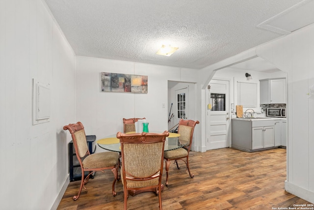 dining room featuring a textured ceiling, light hardwood / wood-style flooring, and sink