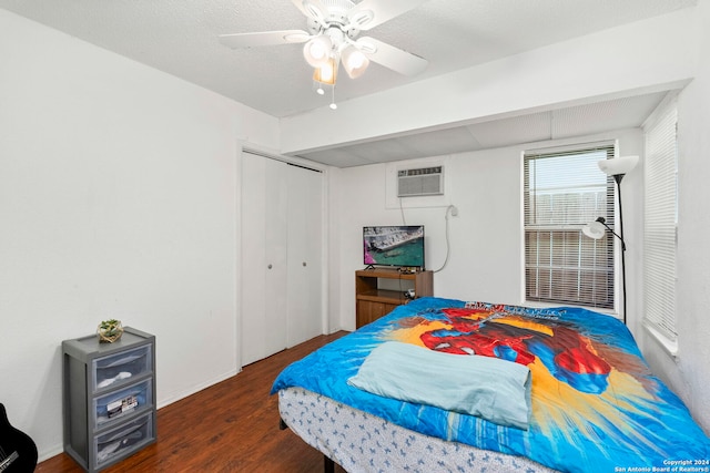 bedroom featuring a textured ceiling, a wall mounted AC, ceiling fan, dark wood-type flooring, and a closet