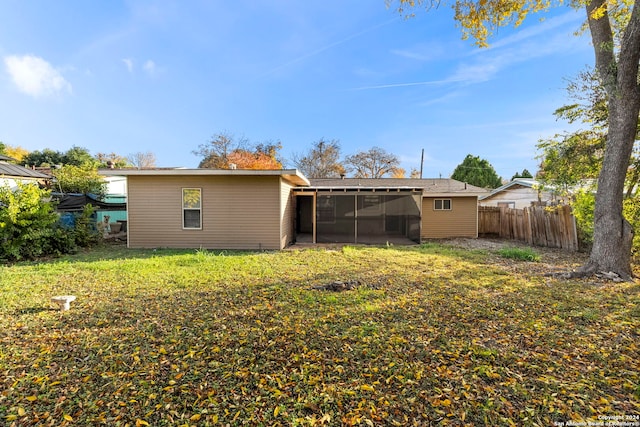 rear view of property with a sunroom and a yard