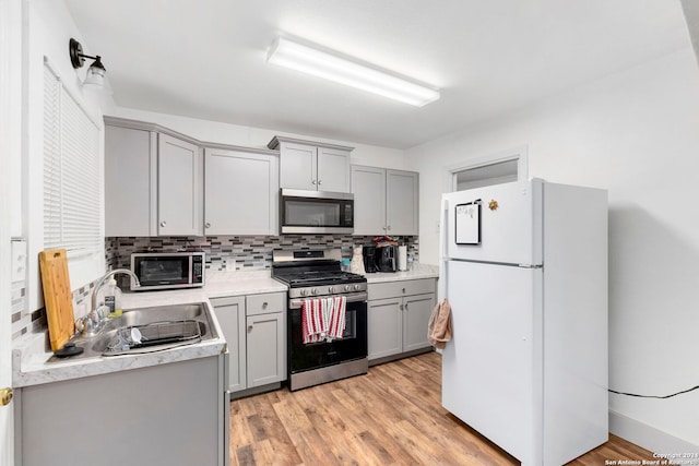 kitchen featuring backsplash, gray cabinets, sink, and stainless steel appliances