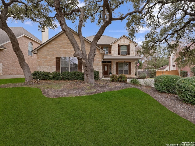 traditional home with a front yard, stone siding, brick siding, and a chimney