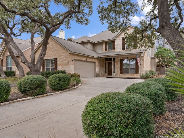 traditional-style home with driveway, stone siding, a garage, and a chimney