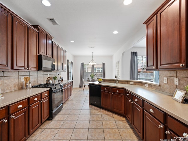 kitchen featuring hanging light fixtures, black appliances, visible vents, and light countertops