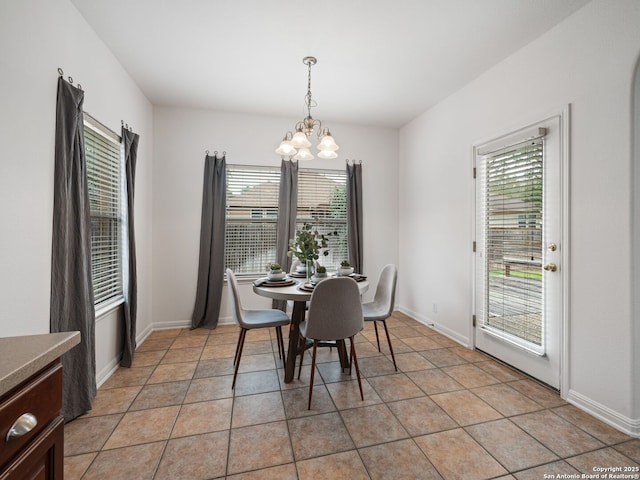 dining space with light tile patterned floors, baseboards, and a notable chandelier