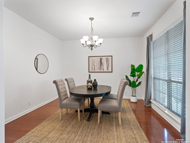 dining room featuring dark wood-style flooring, an inviting chandelier, visible vents, and baseboards