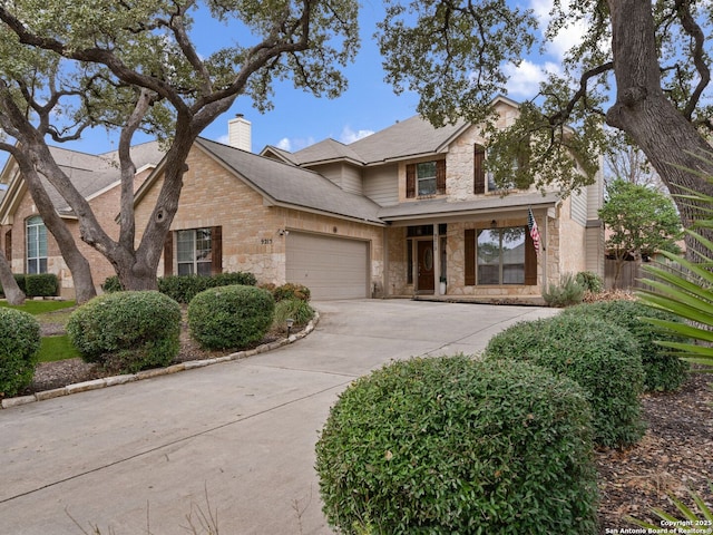 traditional-style house featuring stone siding, driveway, a chimney, and an attached garage