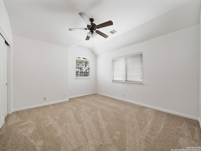 unfurnished room with lofted ceiling, light carpet, visible vents, and baseboards