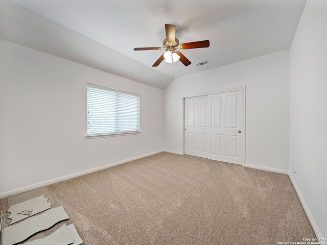 unfurnished bedroom with ceiling fan, carpet flooring, visible vents, baseboards, and vaulted ceiling