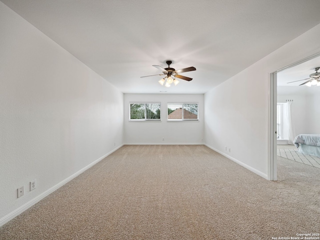 spare room with light carpet, ceiling fan, and baseboards