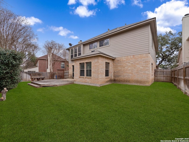 back of house with a lawn, a fenced backyard, a chimney, a deck, and brick siding