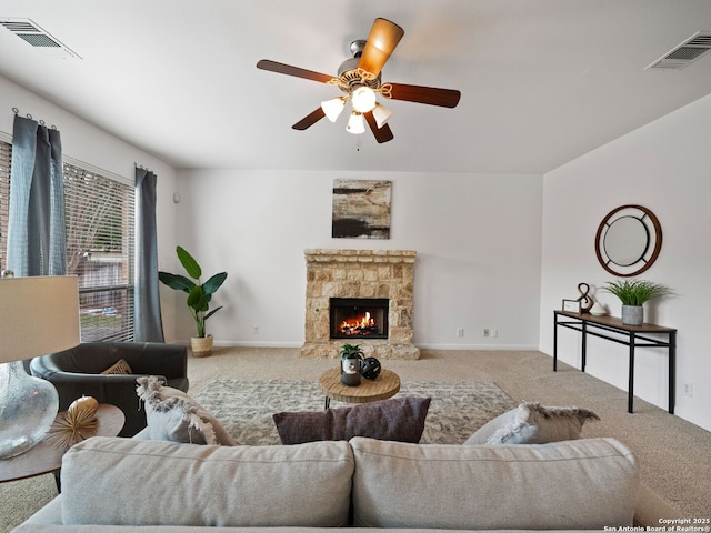 living room featuring light colored carpet, visible vents, ceiling fan, and a stone fireplace