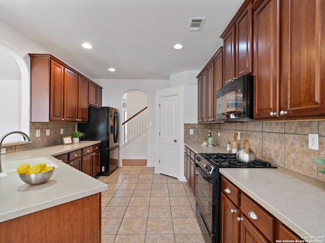 kitchen featuring arched walkways, light tile patterned flooring, a sink, light countertops, and black appliances