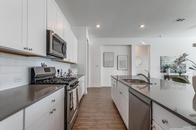 kitchen with sink, white cabinets, hardwood / wood-style floors, and appliances with stainless steel finishes