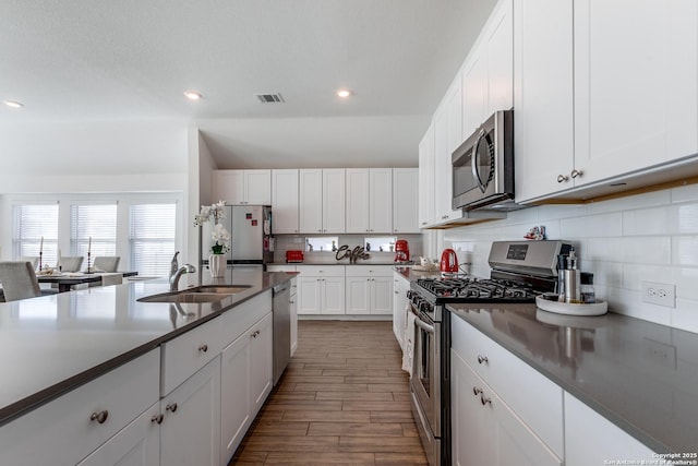 kitchen featuring hardwood / wood-style floors, white cabinetry, sink, and appliances with stainless steel finishes