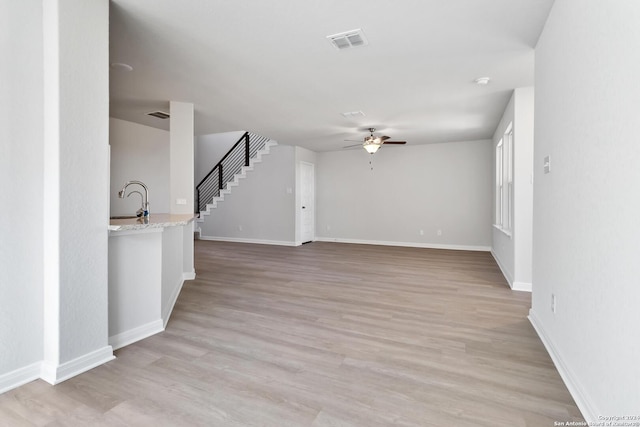 unfurnished living room with ceiling fan and light wood-type flooring