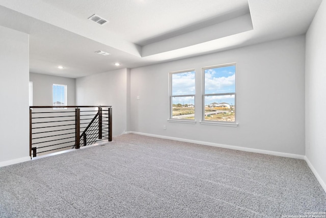 carpeted spare room with a tray ceiling