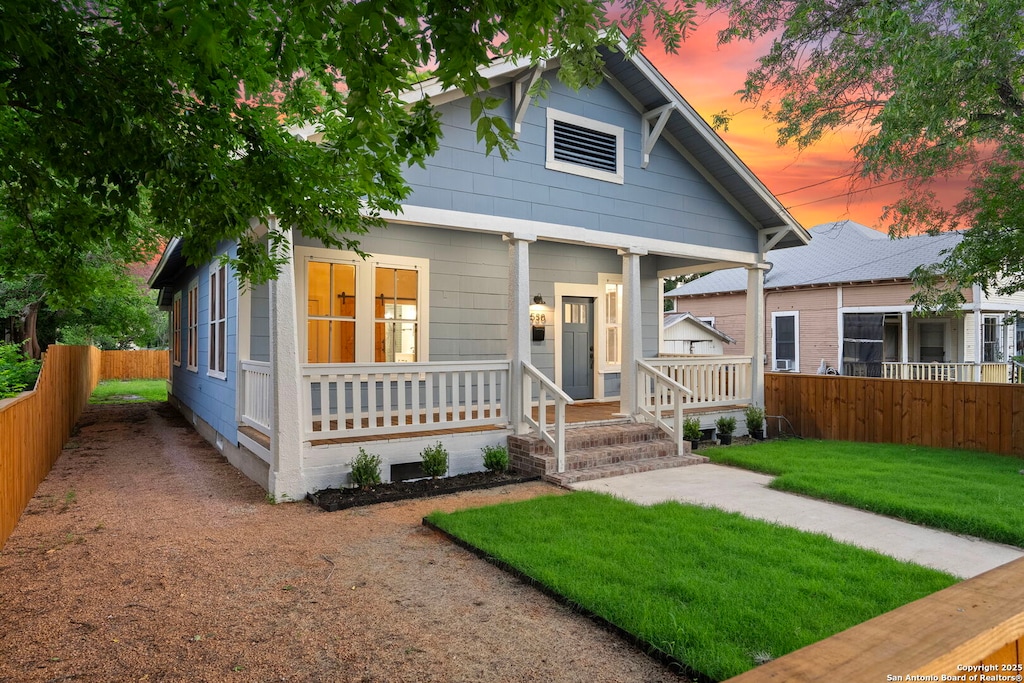 bungalow-style house featuring covered porch and a yard