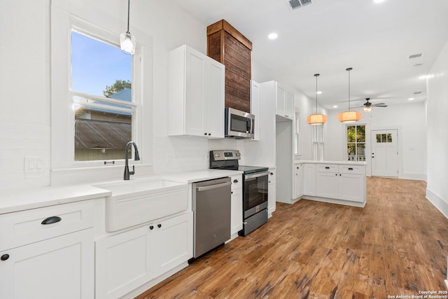 kitchen featuring ceiling fan, decorative backsplash, appliances with stainless steel finishes, decorative light fixtures, and white cabinetry