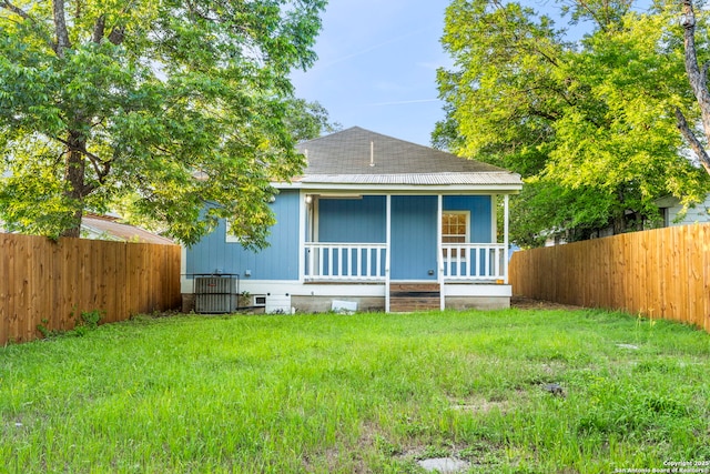 back of house featuring a lawn, cooling unit, and covered porch