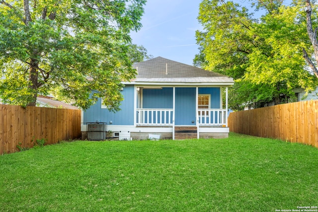 rear view of house with a lawn, covered porch, and central AC unit