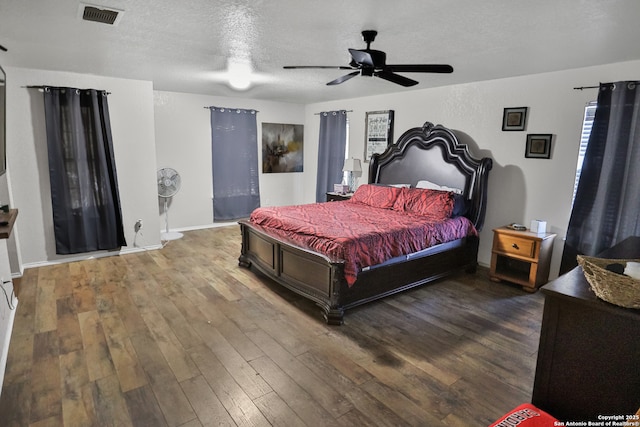 bedroom with a textured ceiling, ceiling fan, and dark wood-type flooring