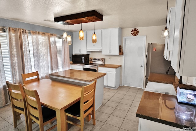 kitchen with white cabinetry, hanging light fixtures, light tile patterned floors, and stainless steel appliances